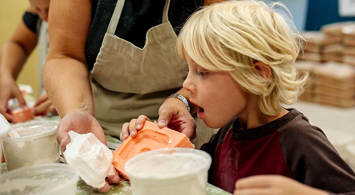 A child looks at a plaster cast of a fossil.