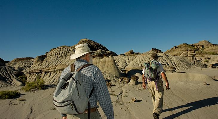 Two people walk in the badlands.