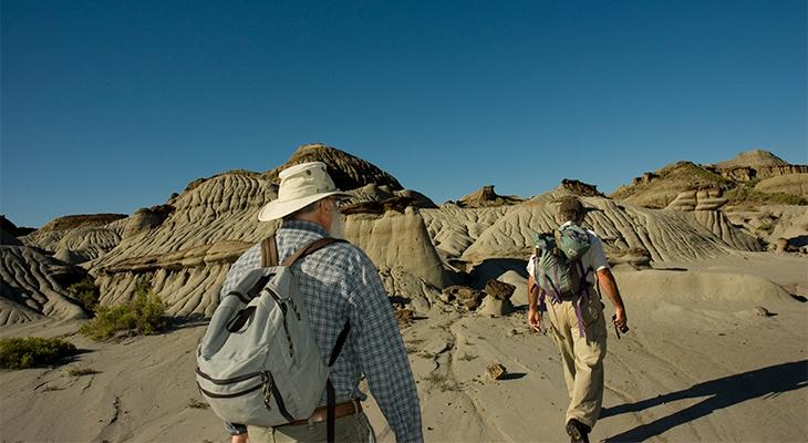 Two people walk in the badlands. 